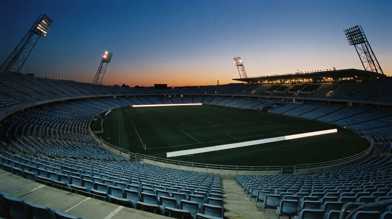 An empty football stadium with floodlight masts at dusk