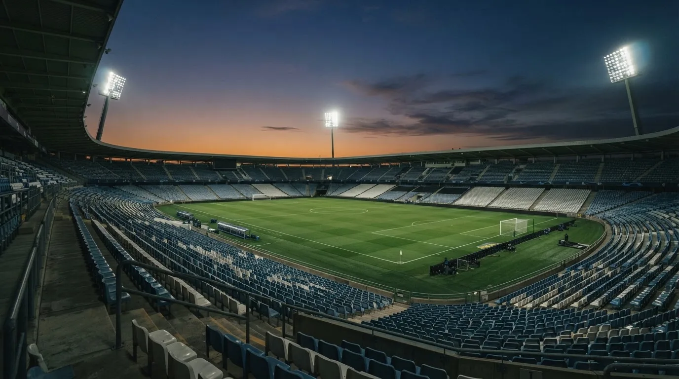 An empty football stadium with floodlight masts at dusk
