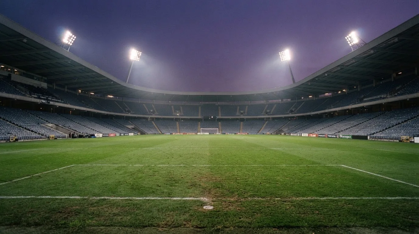 An empty football stadium with floodlight masts at dusk