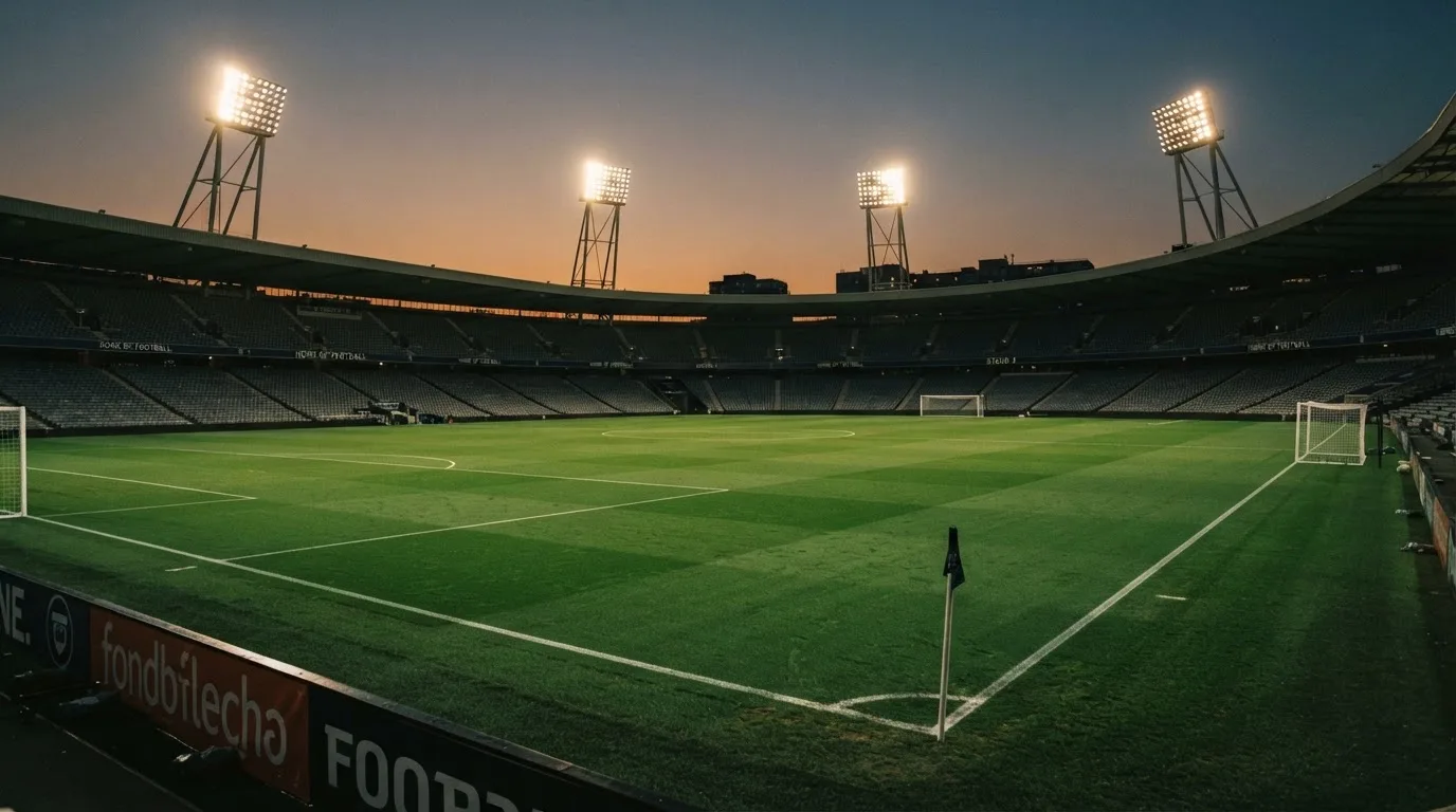 An empty football stadium with floodlight masts at dusk