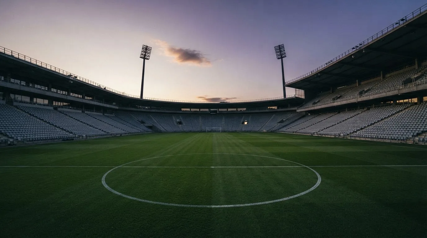 An empty football stadium with floodlight masts at dusk