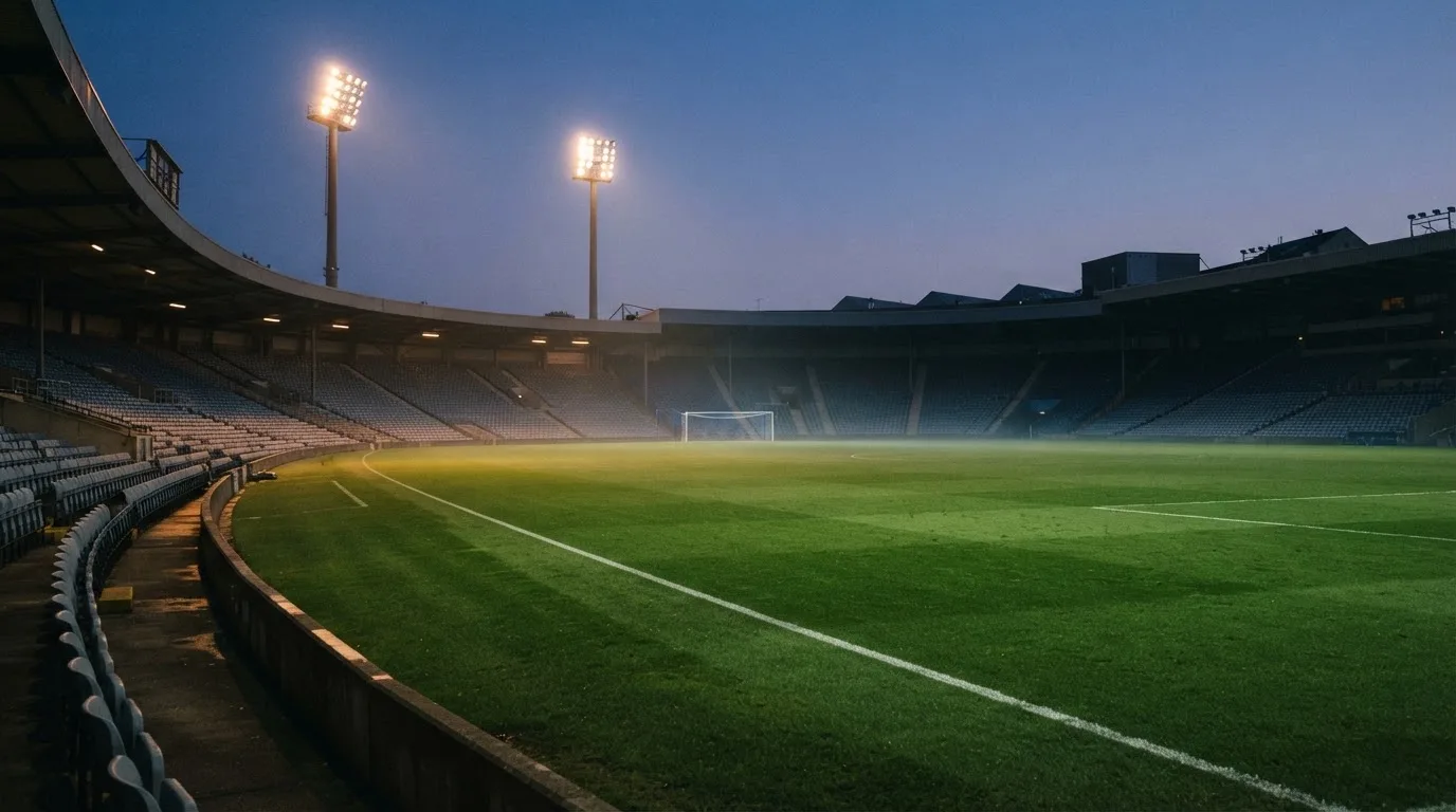 An empty football stadium with floodlight masts at dusk