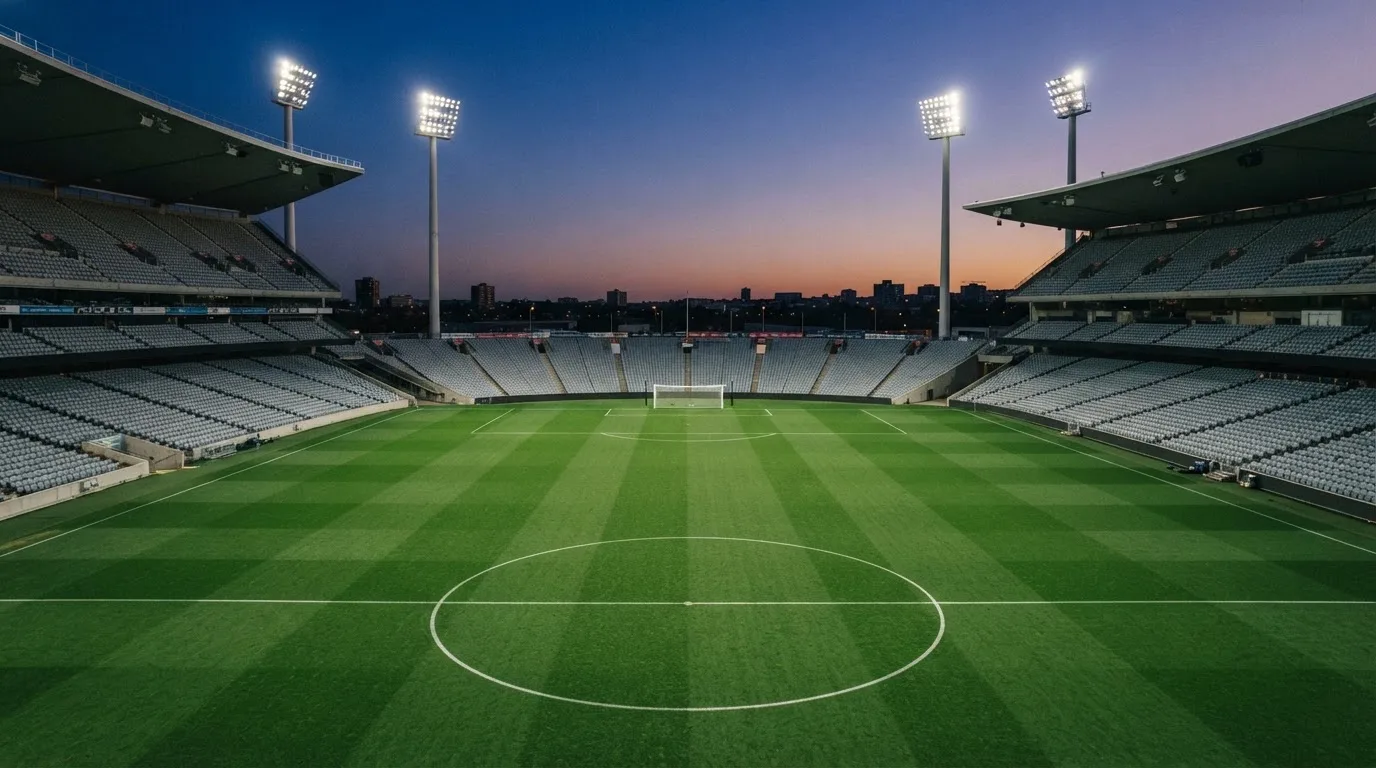 An empty football stadium with floodlight masts at dusk