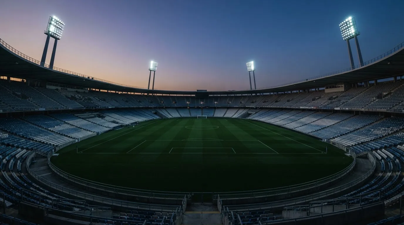 An empty football stadium with floodlight masts at dusk