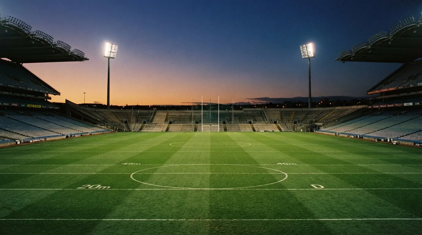 An empty football stadium with floodlight masts at dusk