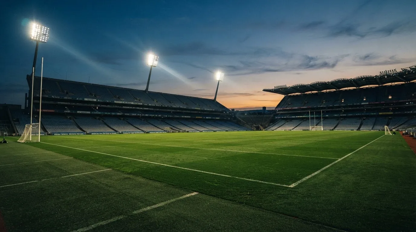 An empty football stadium with floodlight masts at dusk