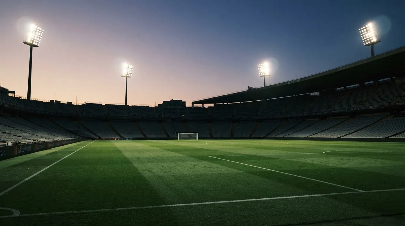 An empty football stadium with floodlight masts at dusk