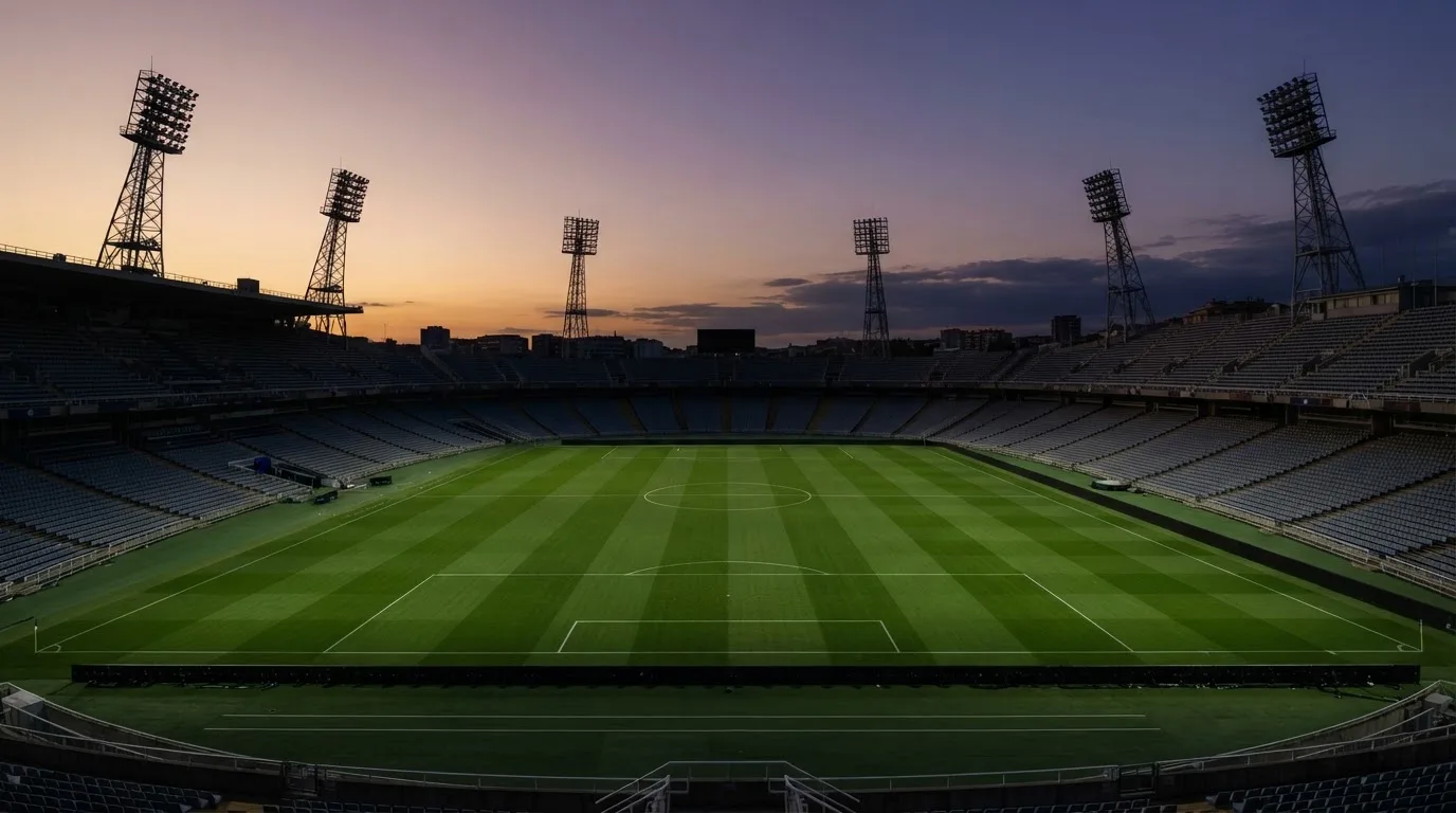 An empty football stadium with floodlight masts at dusk