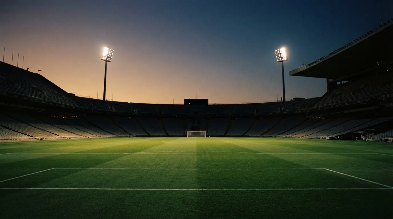 An empty football stadium with floodlight masts at dusk