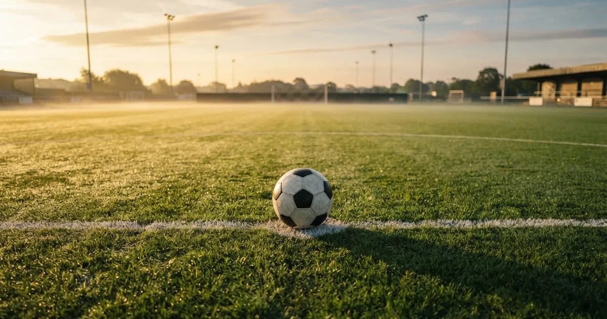 A ball on the centre spot of a grass pitch in morning light