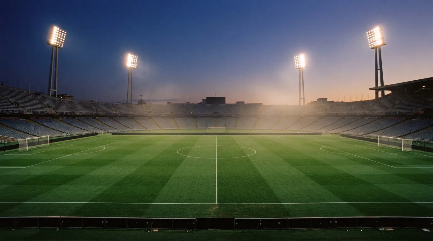 An empty football stadium with floodlight masts at dusk