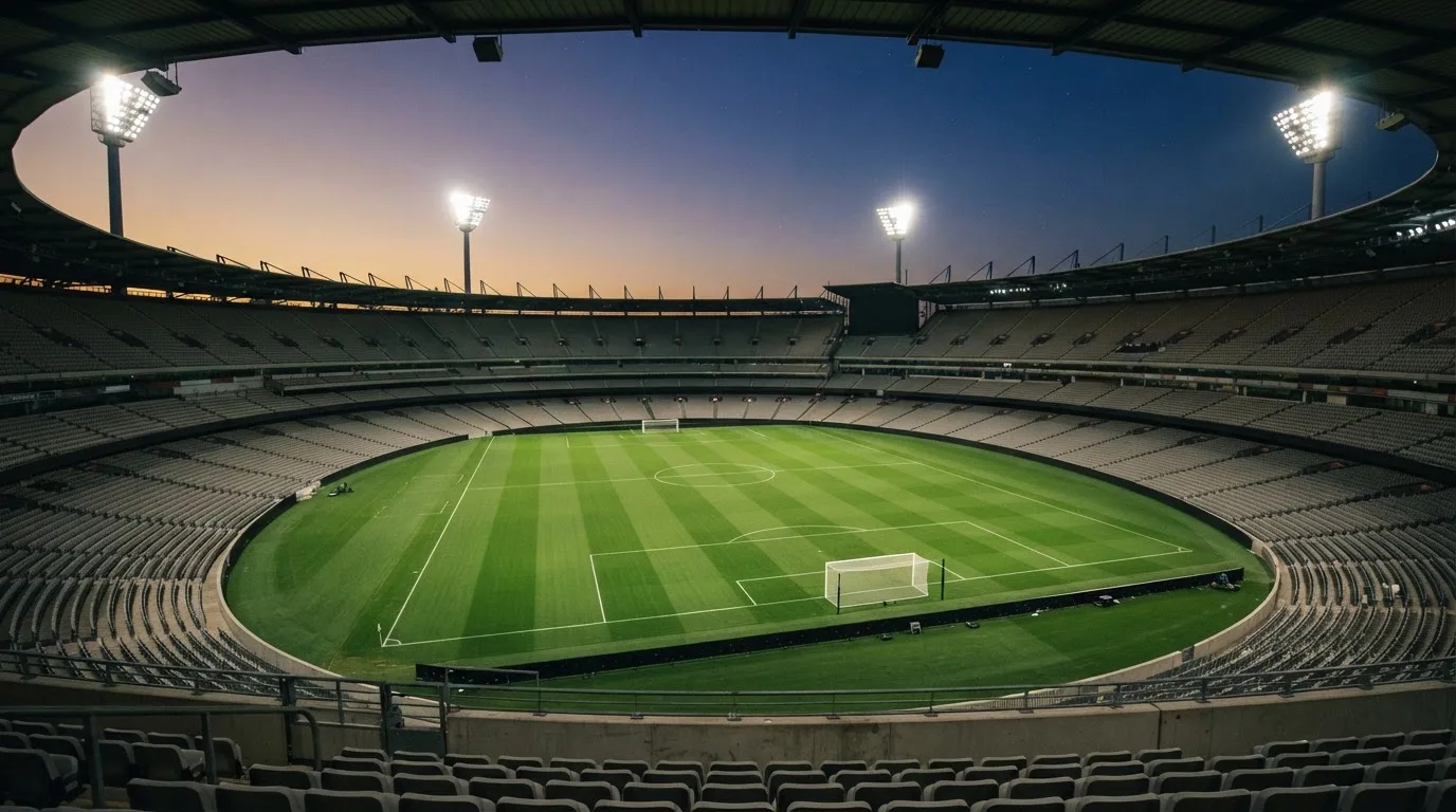 An empty football stadium with floodlight masts at dusk