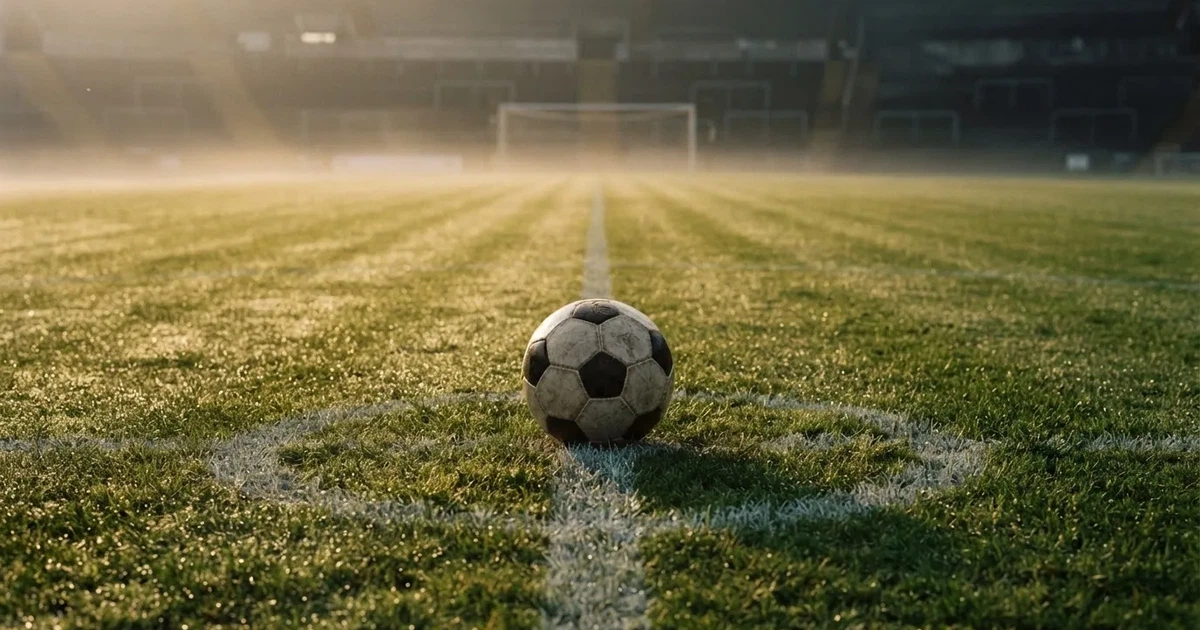 A ball on the centre spot of a grass pitch in morning light
