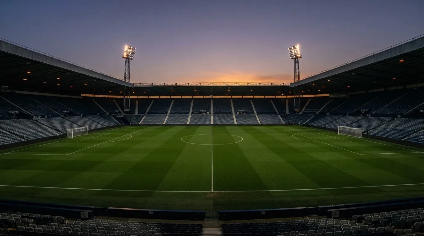 An empty football stadium with floodlight masts at dusk