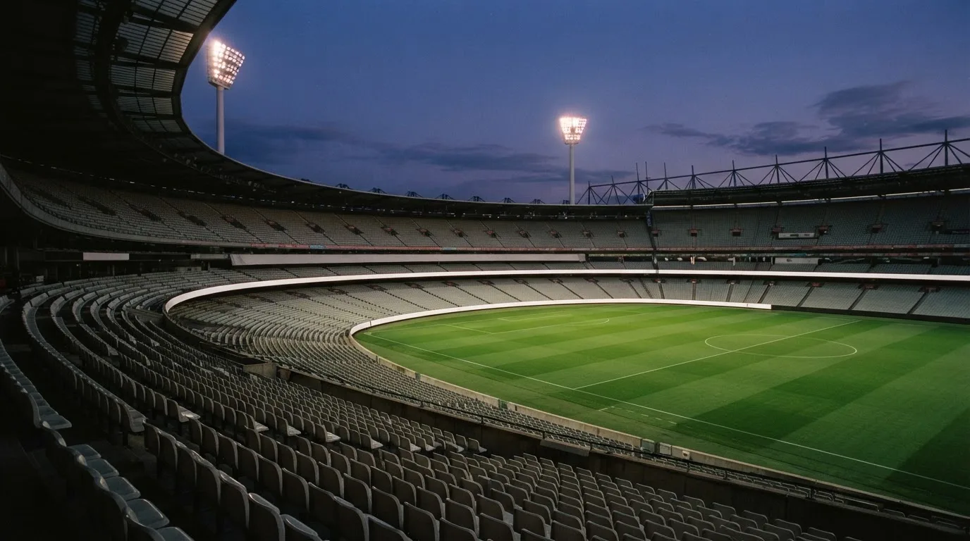 An empty football stadium with floodlight masts at dusk